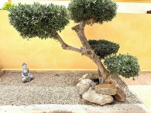A bonsai tree with a Buddha statue in a rock garden. - Cosy detached villa for 4 persons with private pool, family-friendly (Mazarrón)