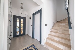 A hallway with a glass door, a staircase, and a patterned rug.