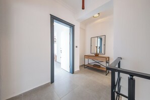 Un couloir avec une console en bois, un miroir et une porte donnant sur une autre pièce.