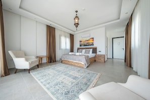Ein modernes Hotelzimmer mit einem großen Bett, einer Sitzecke, einem kleinen Tisch und Blick auf die Stadt.