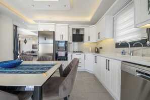 A modern kitchen with white cabinetry, a built-in oven, and a dishwasher.