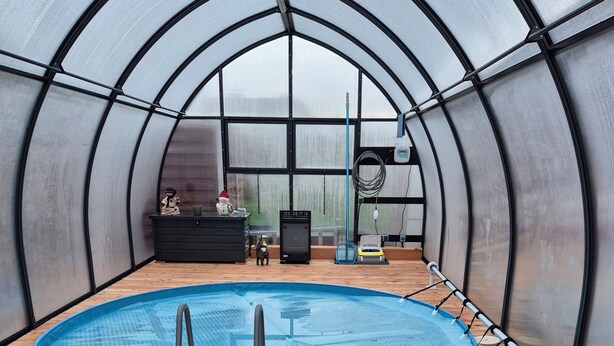 An indoor swimming pool with a diving board, surrounded by wooden decking and seating areas. - Apartment (Brunsbüttel)