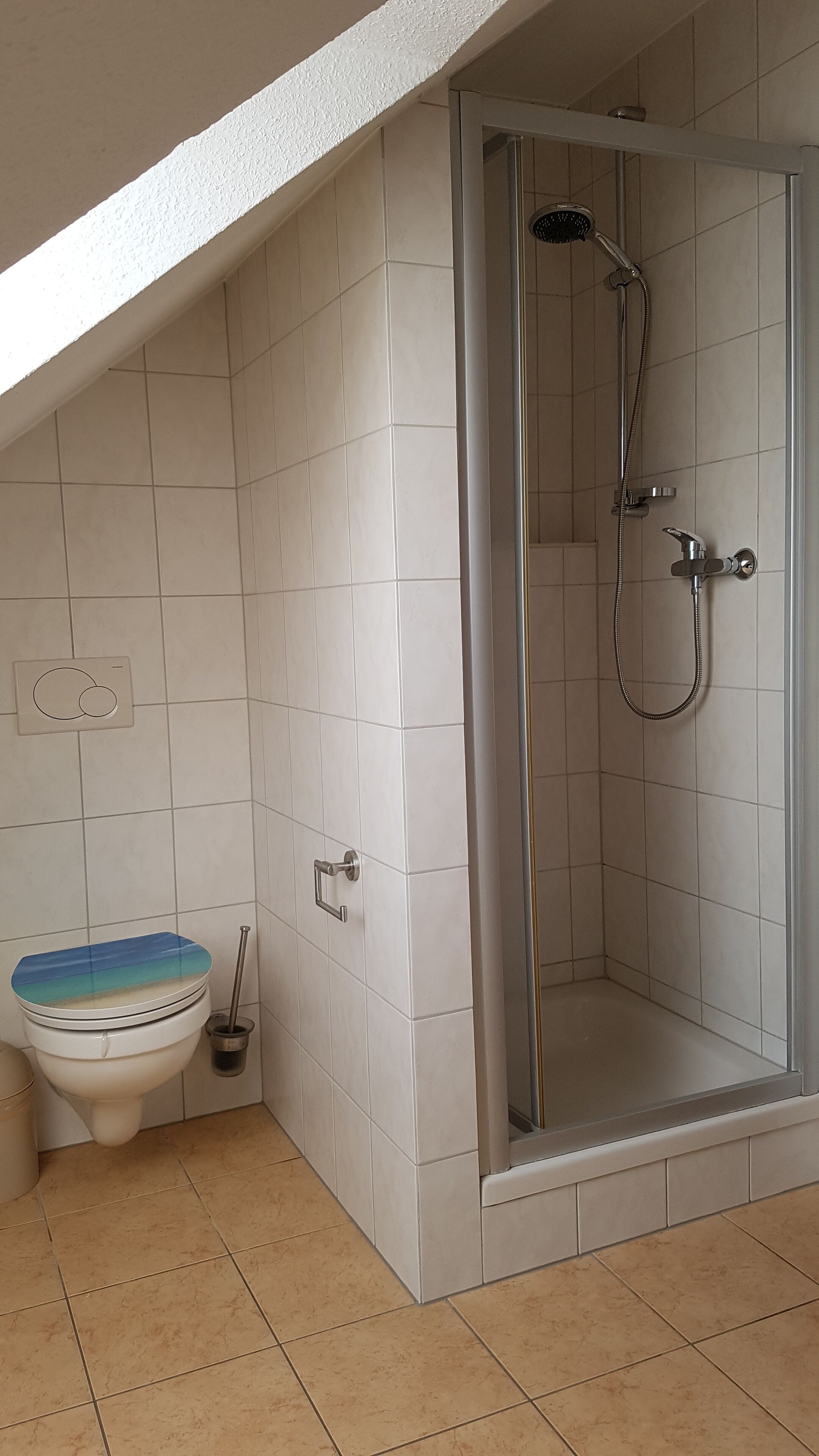 Un baño con inodoro, ducha y paredes de azulejos.