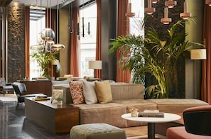Um lobby moderno com um sofá, um balcão de recepção e uma planta grande.