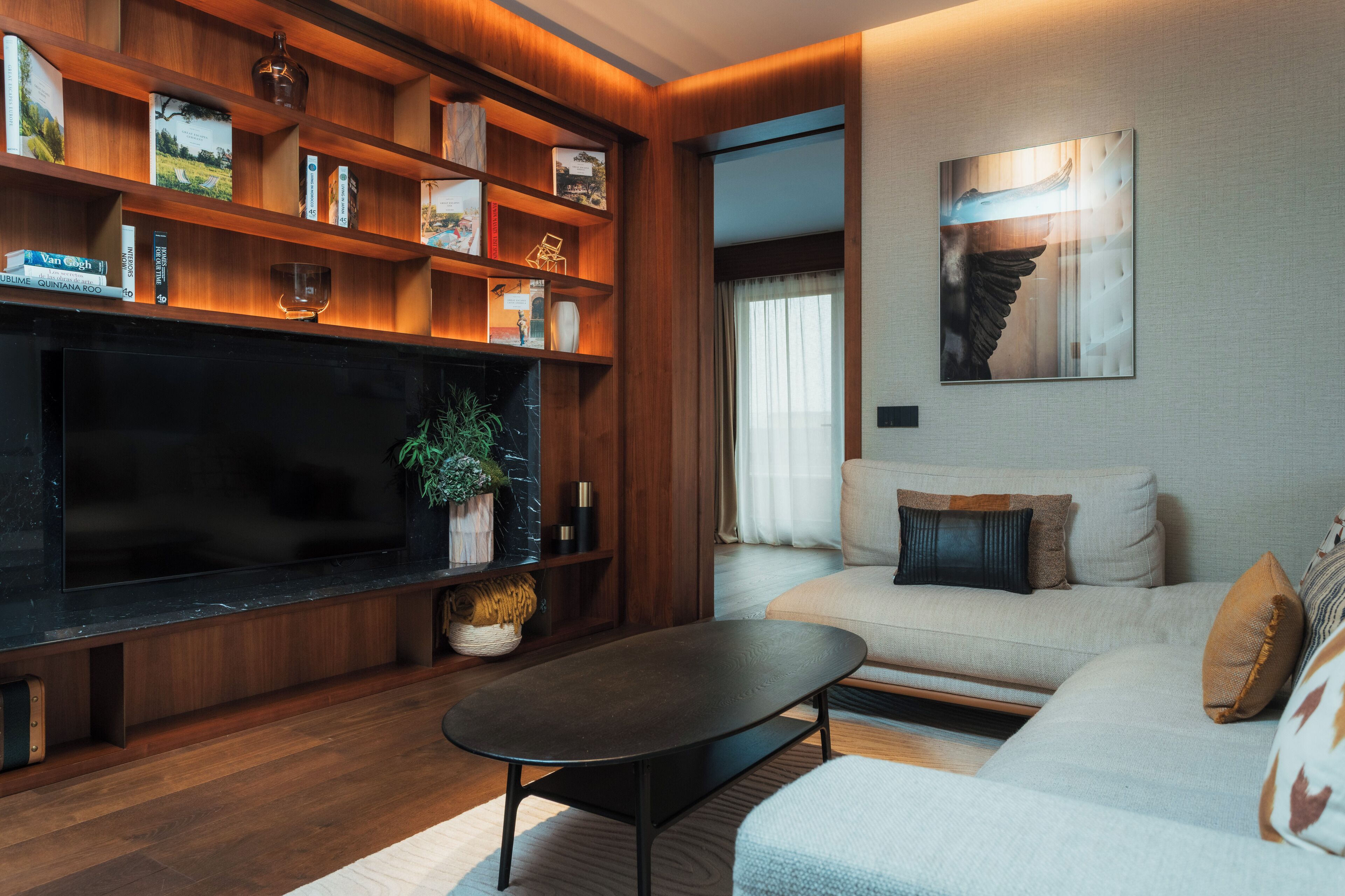 Een moderne woonkamer met een flatscreen televisie, houten planken, een bank en een salontafel.