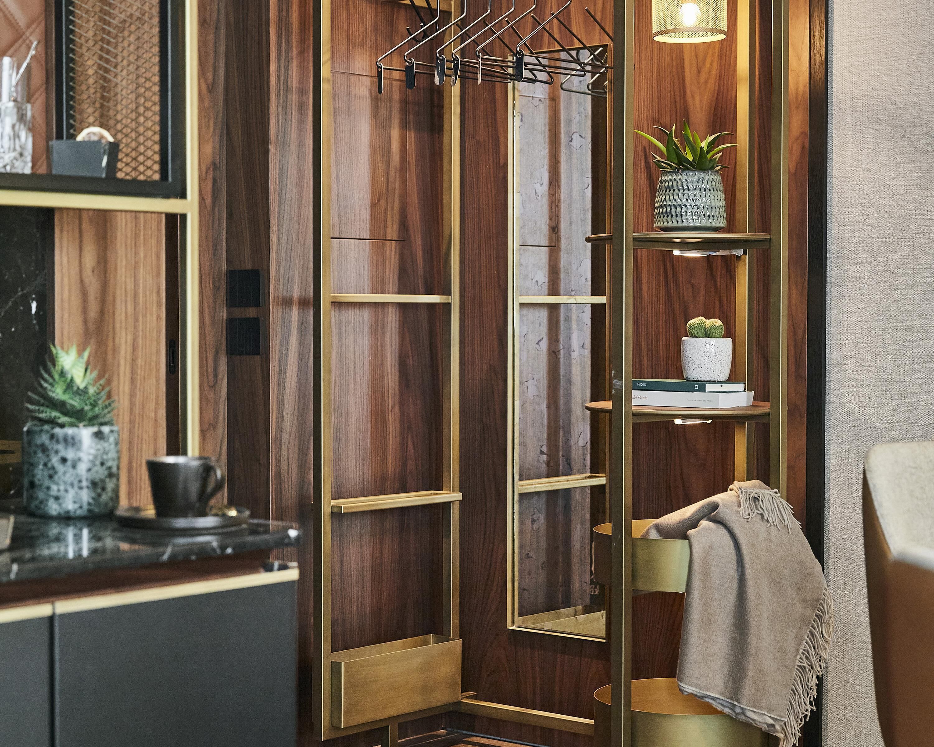 Un interior de madera con una estantería metálica tipo escalera, una planta en maceta y una toalla en una silla.