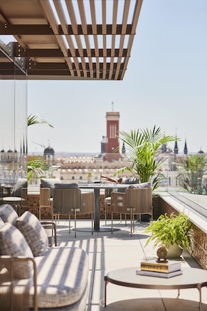 Terraço no topo com móveis de exterior, uma mesa e plantas em vasos.