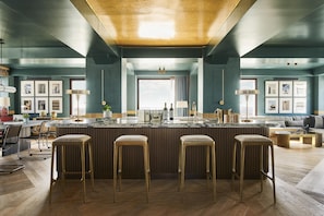 A modern kitchen with a central island, bar stools, and a view to the outside.