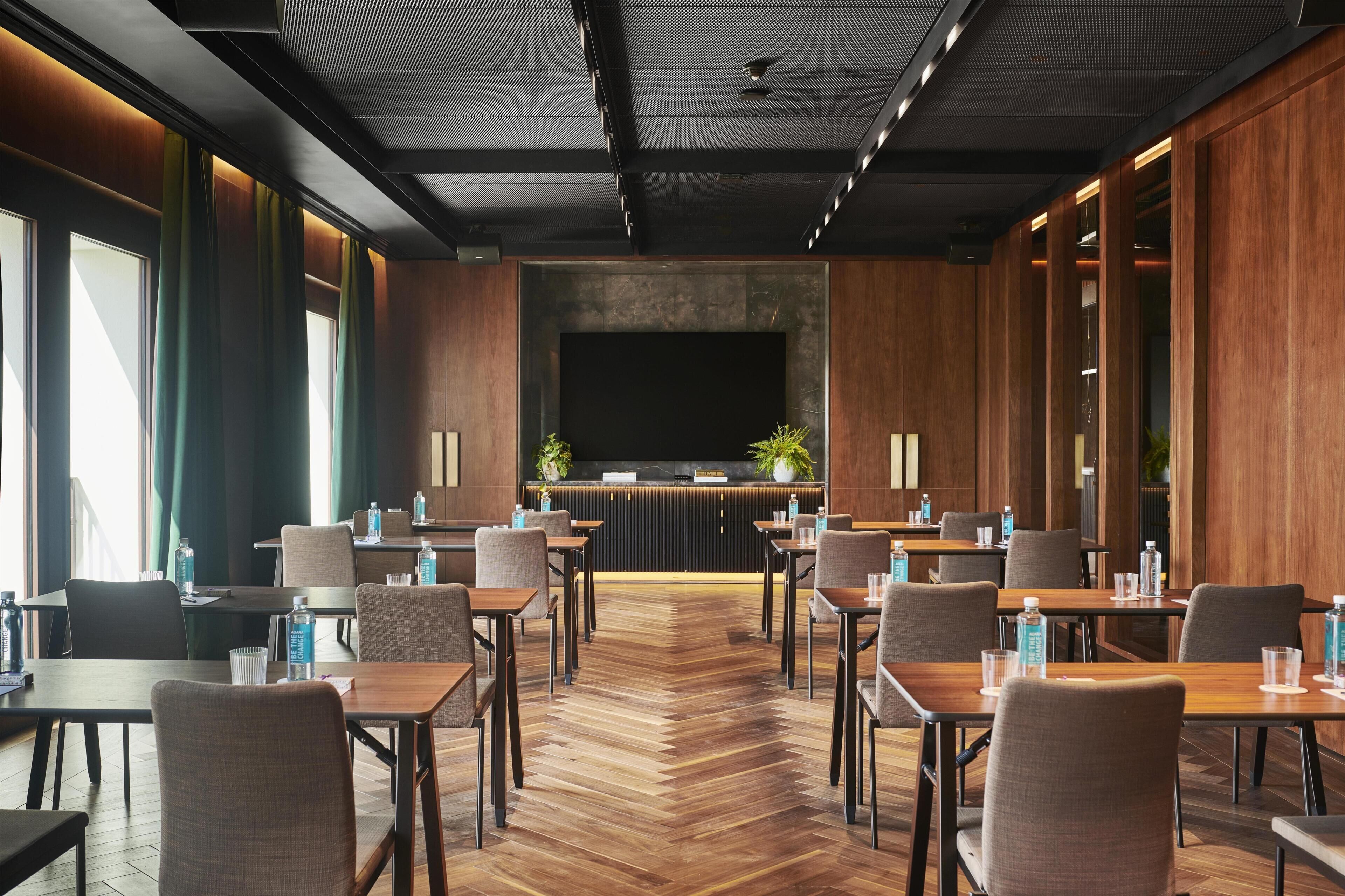 Eine moderne Hotelhalle mit einer zentralen Rezeption, mehreren Sitzbereichen und einem Zargenholzboden.
