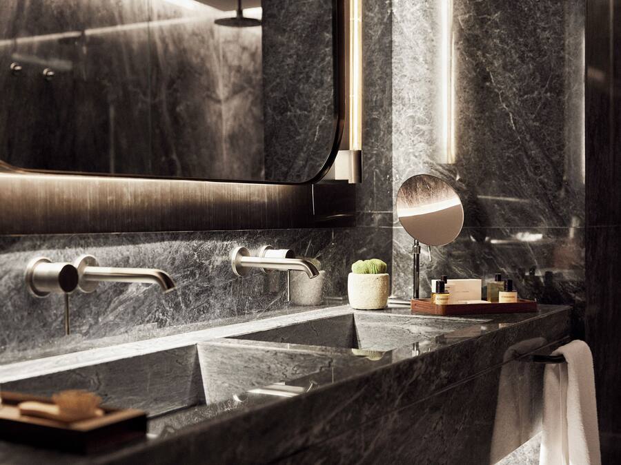 A modern bathroom with a marble sink, a mirror, and a small plant.