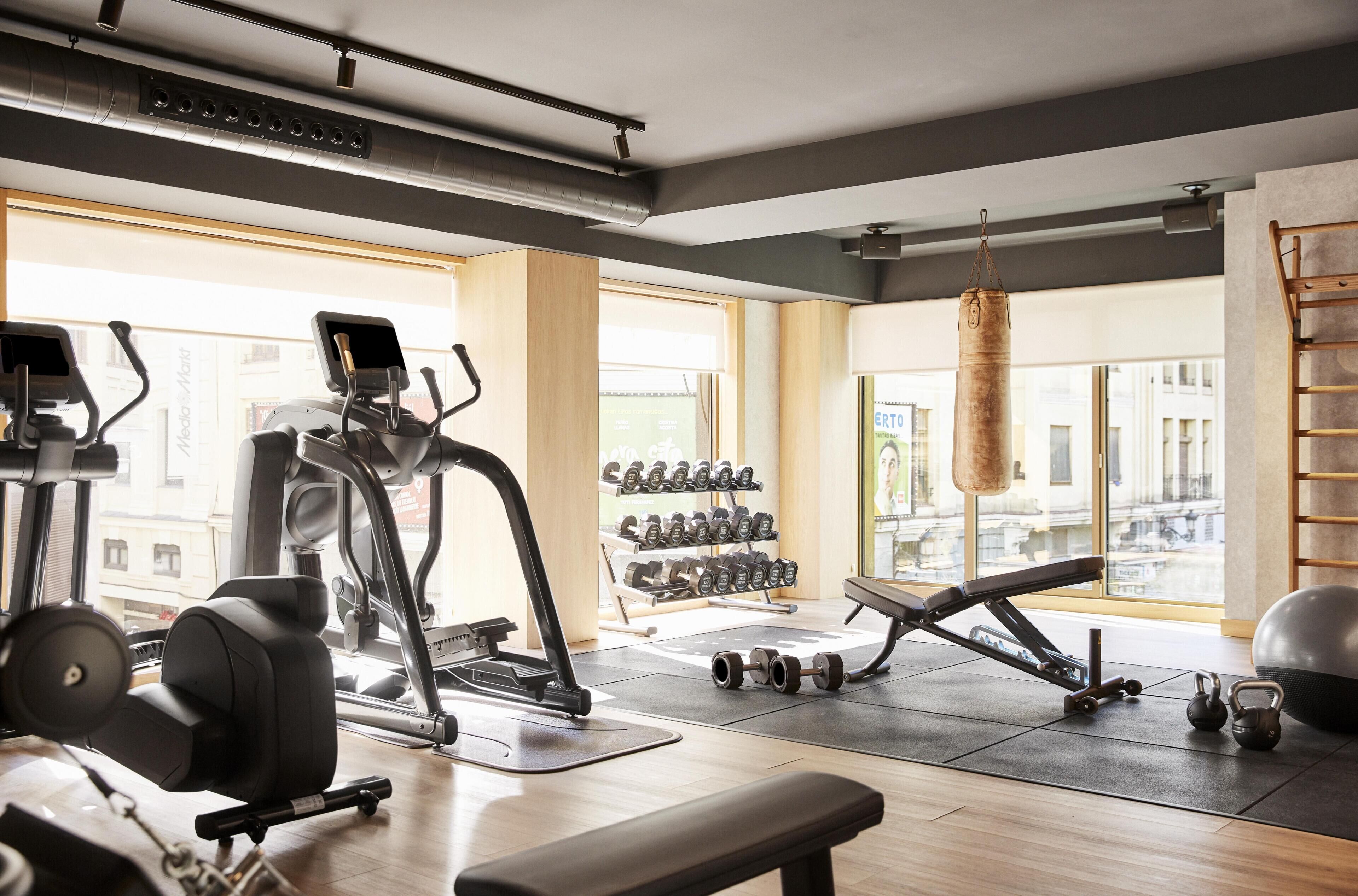 Gimnasio con equipo de ejercicio, una banca, mancuernas y un saco de boxeo.