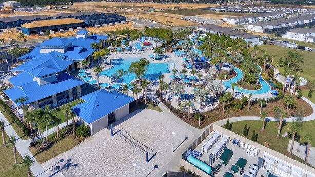 Vista aérea de un complejo turístico con varias piscinas, una piscina central amplia y diversos edificios con techos azules.