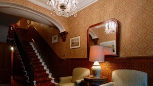 A room with a red carpet, two armchairs, a lamp, a mirror, and a staircase. - Manoir Sainte Geneviève (Québec City)