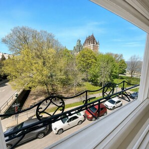 A view from a window overlooking a parking area with cars, trees, and a historic building in the background. - Manoir Sainte Geneviève (Québec City)