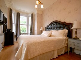 Un dormitorio ordenado con una cama grande, una mesita de noche con lámpara y un aparador.