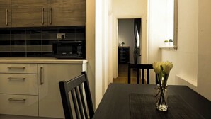 Una cucina con mobili in legno scuro, un forno a microonde e un tavolo da pranzo con un vaso di fiori.
