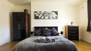 Una camera da letto con un letto, un armadio, una cassettiera e un grande quadro floreale appeso al muro.