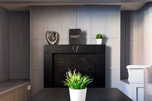 A modern fireplace with a black mantel, a heart-shaped decoration, and a small potted plant.