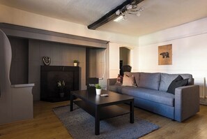 A modern living room with a grey sofa, a black coffee table, and a fireplace.