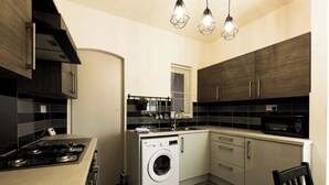 Una cucina compatta con piano cottura a gas, lavatrice integrata e forno a microonde.