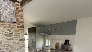 Une cuisine moderne avec un mur en pierre, une table à manger avec des chaises et un canapé en cuir noir.