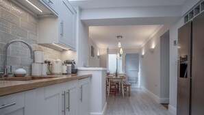 A modern kitchen with white cabinetry, a wooden countertop, and a stainless steel refrigerator. - Noe Acre - 3 Bedroom Cottage - Tenby (Tenby)