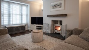 A cozy living room with a fireplace, comfortable seating, and a television. - Noe Acre - 3 Bedroom Cottage - Tenby (Tenby)