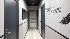 A hallway with a door at the end, a wall with a feather design and text, and a light fixture on the ceiling. - Apartment in Cannes (Cannes)