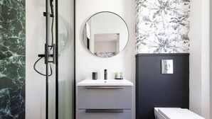 A bathroom with a glass shower enclosure, a white sink with a mirror, and a toilet. - Apartment in Cannes (Cannes)