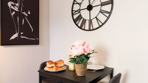 A dining area with a table set for two, a clock, and a framed artwork on the wall. - Apartment in Cannes (Cannes)