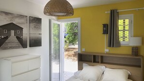 A bedroom with a bed, a dresser, a window with curtains, and a door leading to an outdoor area. - Bleu Comme Toit 3425 (Les Issambres)