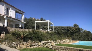 A house with a pool, a covered patio, and a stone retaining wall. - Bleu Comme Toit 3425 (Les Issambres)