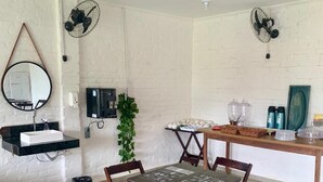 A dining area with a table and chairs, a hanging mirror, and two wall-mounted fans. - Hotel colonial lençóis Paulista (Lencois Paulista)