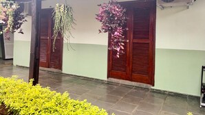 A building with a tiled floor, wooden doors, and hanging plants. - Hotel colonial lençóis Paulista (Lencois Paulista)