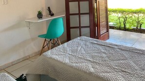 A bedroom with a bed, a desk, a chair, a TV, and a sliding door to a balcony. - Hotel colonial lençóis Paulista (Lencois Paulista)