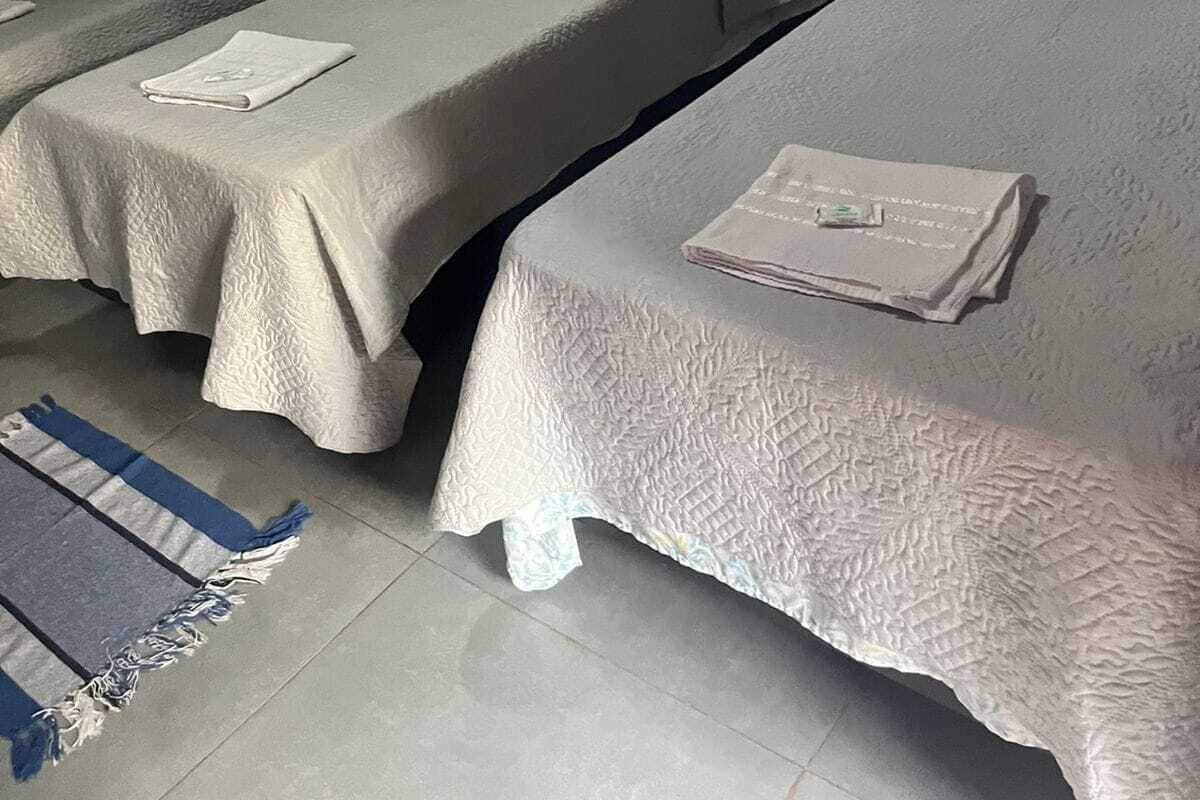 Une chambre d’hôtel avec deux lits simples, une tête de lit en bois, un rideau gris orné de motifs en forme d’étoiles et un petit tableau encadré accroché au mur.
