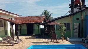 A swimming pool with a tiled deck, lounge chairs, and a water tower in the background. - Hotel colonial lençóis Paulista (Lencois Paulista)