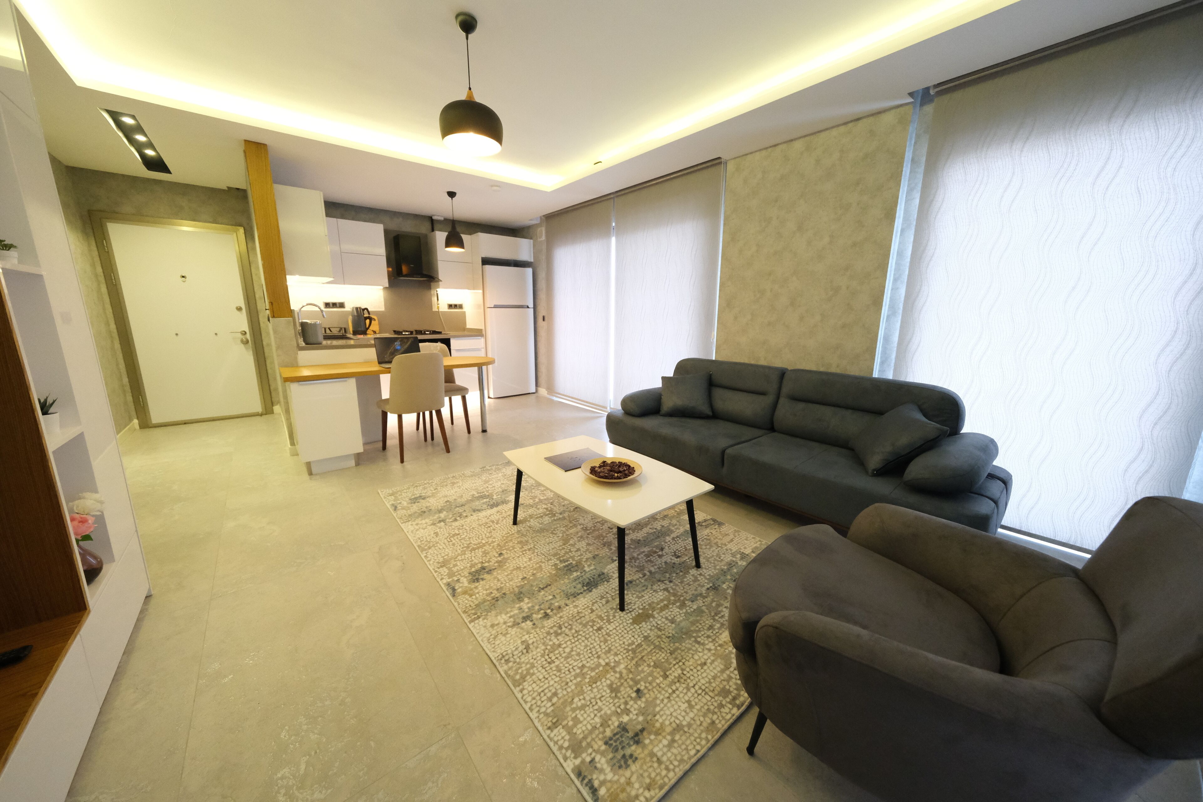 Un salon moderne avec un canapé, une table basse et une cuisine en arrière-plan.