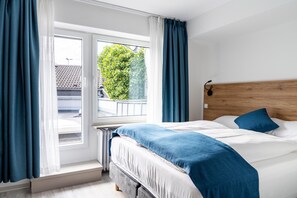 A bedroom with a bed, curtains, a window, and a view of greenery outside. - HOTEL83 (Bonn)