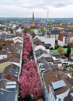 A cityscape with a row of buildings, a church spire, and a factory chimney.