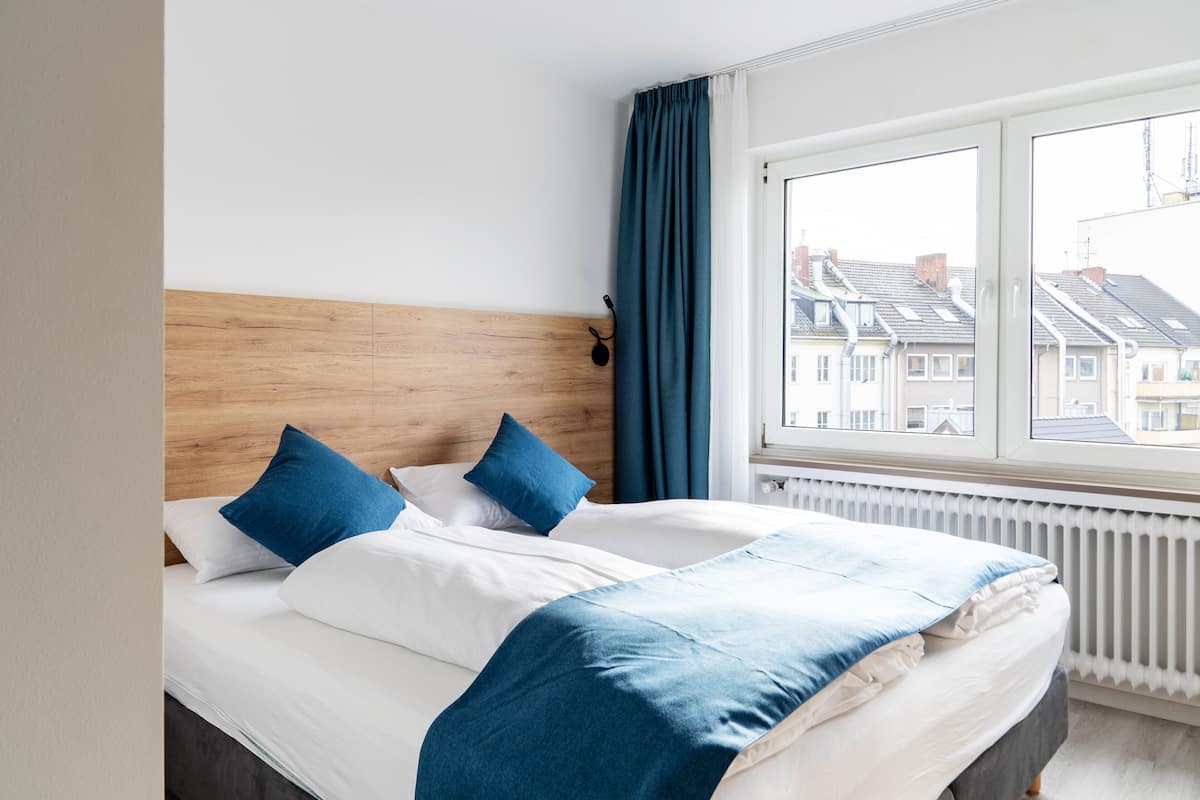 A double bed with a wooden headboard, white bedding, and blue accents.