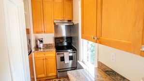 Una cocina compacta con armarios de madera, electrodomésticos de acero inoxidable y encimera de granito.
