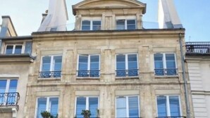 A multi-story building with a classical architectural style, featuring a symmetrical facade, multiple windows, and decorative iron railings on the balconies. - Stunning studio with lift - Louvre (Paris)