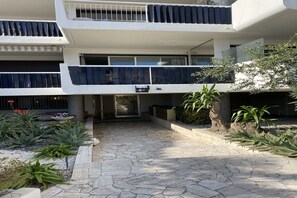 Un immeuble à plusieurs niveaux doté d’une cour pavée de pierres, de plantes d’extérieur et d’une entrée fermée par un portail.