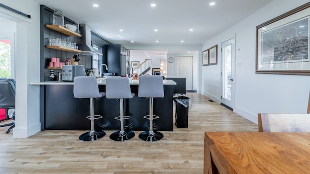 Een moderne keuken met een centraal eiland, barstoelen en inbouwplanken.