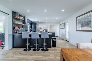 Een moderne keuken met een centraal eiland, barstoelen en inbouwplanken.