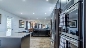 Een moderne keuken met een centraal eiland, roestvrijstalen apparatuur en een houten vloer.