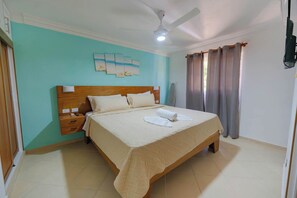 A bedroom with a bed, a nightstand, a ceiling fan, and a wall-mounted artwork. - Sosúa Condo: Pool, A/C, Steps to Beach & Nightlife (Sosúa)