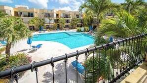 Un hôtel doté d’une piscine entourée de palmiers et de chaises longues.