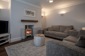 A cozy living room with a fireplace, a sofa, a TV, and a decorative rug.